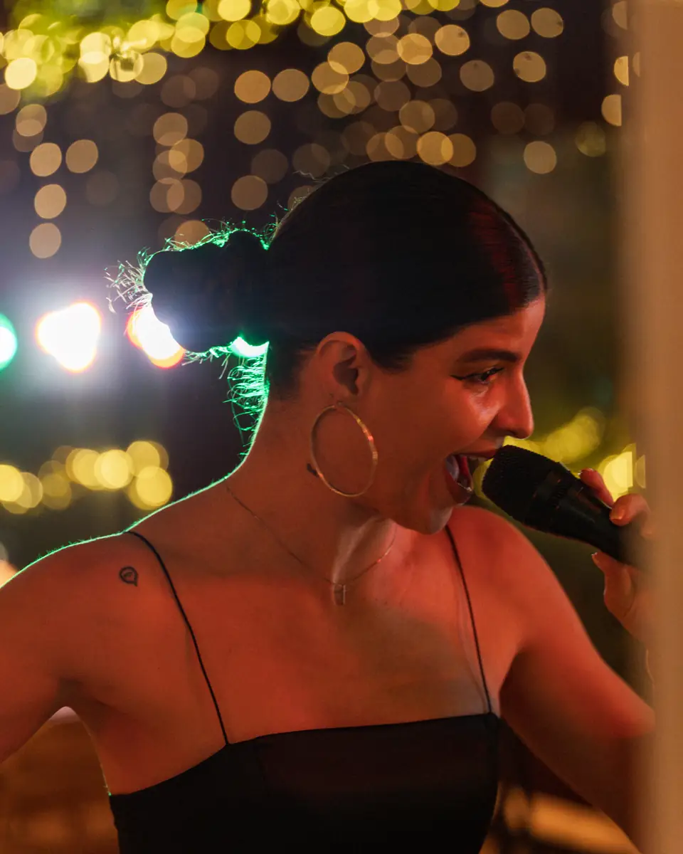 A singer in profile with the terrace lanterns glowing behind her