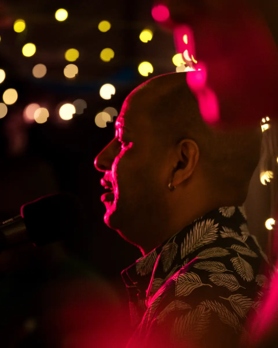 A singer at the microphone under magenta stage light at Pachamama