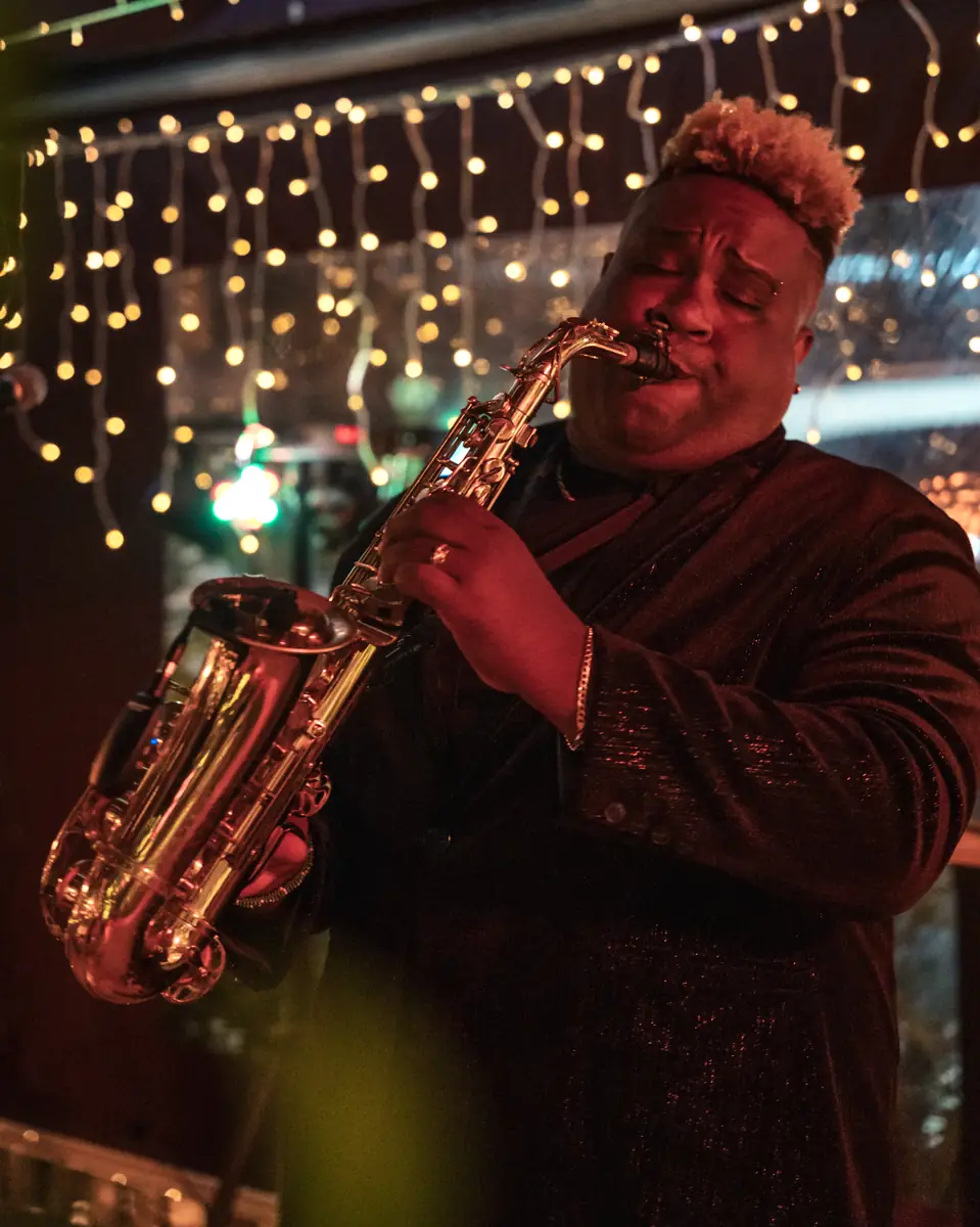 A saxophone player performing in red light at Pachamama