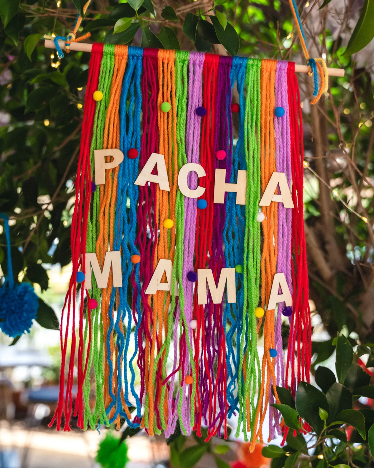 A handmade woollen banner spelling Pachamama, hung in the greenery outside the restaurant