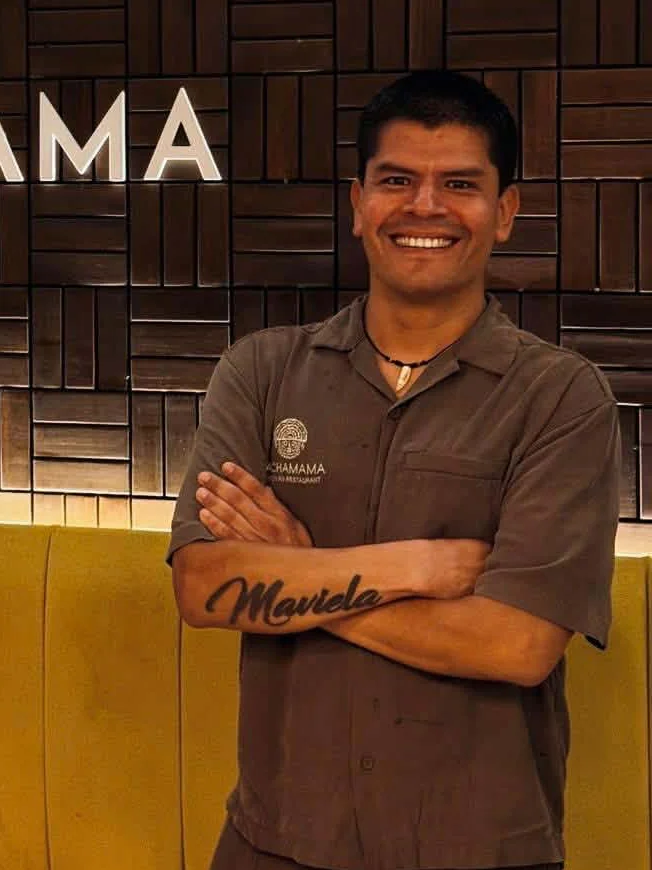 Un integrante del equipo de Pachamama junto al cartel del restaurante