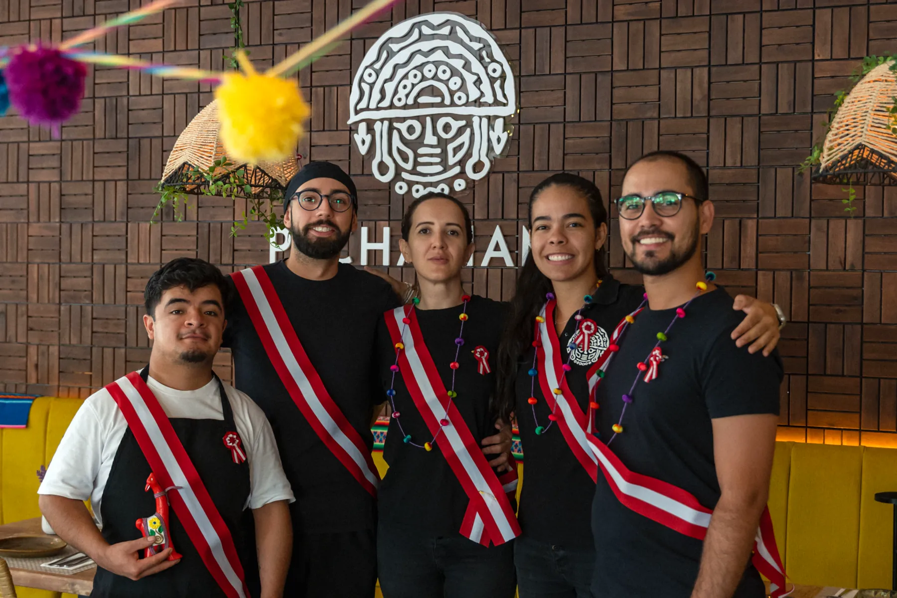 The Pachamama team together in the dining room, wearing Peruvian sashes