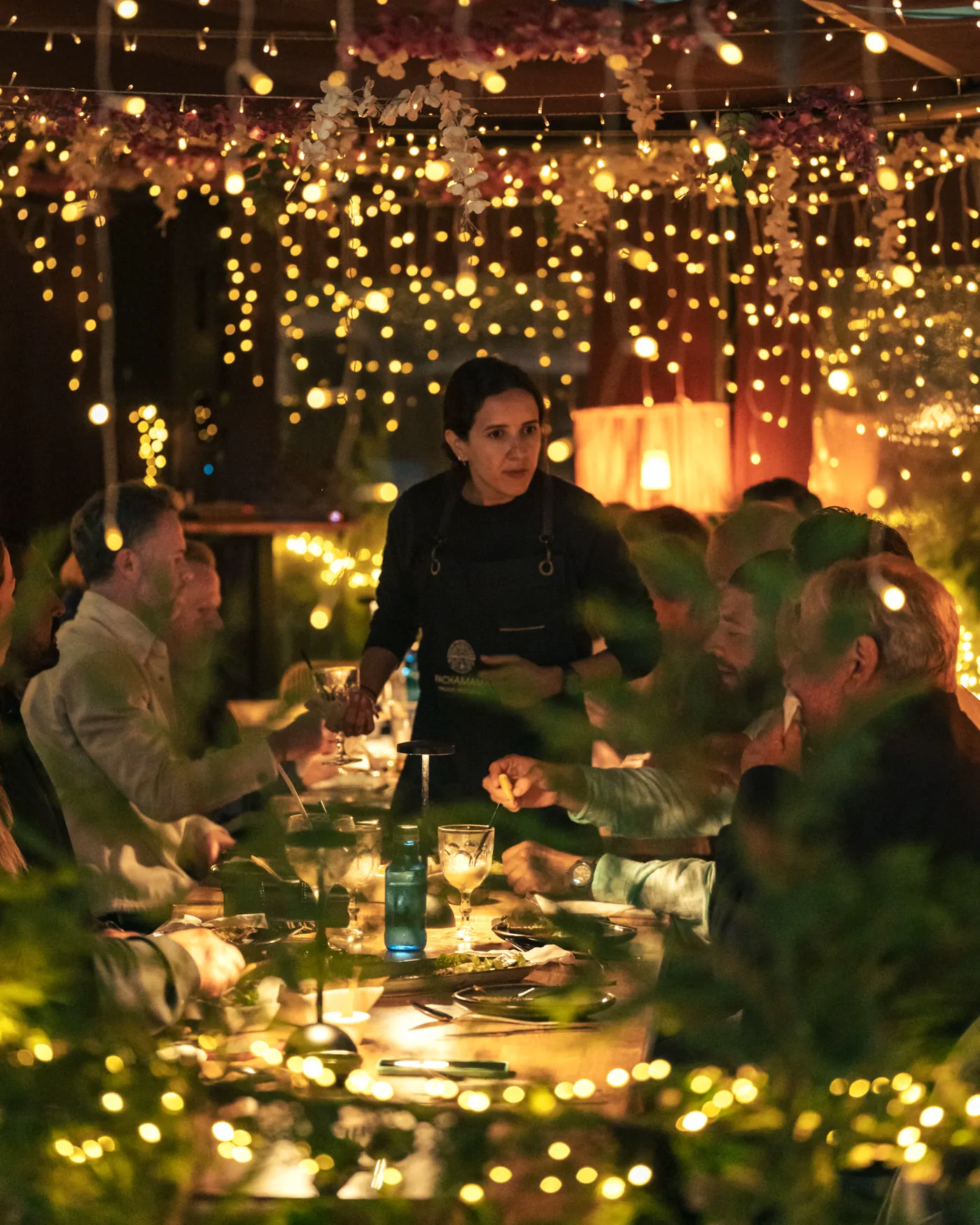 A long table set for a company Christmas dinner under the string lights at Pachamama